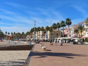 people walking on a beach with palm trees and buildings at Pizarro Apartment in Villajoyosa