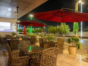 a restaurant with tables and chairs and red umbrellas at فندق قمة البستان in Quai