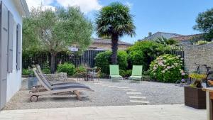 een patio met stoelen, een tafel en een palmboom bij Au lieu dit La Passe , Villa individuelle de plain pied, avec beaucoup de charme in La Couarde-sur-Mer