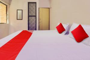 Cette chambre comprend un lit avec des oreillers rouges et blancs. dans l'établissement Hotel O Delight Inn, à Rāipur
