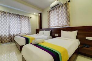 two beds in a hotel room with curtains at Hotel Victoria City Mumbai in Mumbai