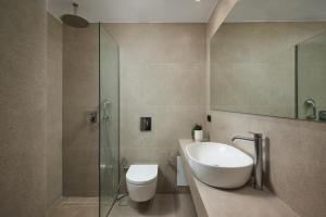 a bathroom with a sink and a toilet and a glass shower at Cityloft Avenue in Mastambás +19 photos