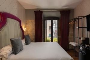 une chambre avec un grand lit blanc et une fenêtre dans l'établissement Hotel Don Juan Boutique, à Úbeda