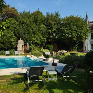 einen Garten mit Pool und Stühlen und ein Haus in der Unterkunft Logis des Tourelles Appartement in Cognac