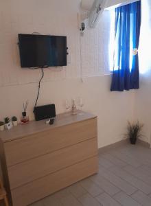 Un televisor de pantalla plana colgado en una pared con una cómoda. en La Dimora Di Bruna, en Nápoles