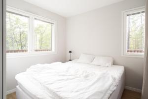 a white bedroom with a large white bed with two windows at Villa MiaEmilia B in Espoo