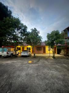a yellow building with cars parked in a parking lot at อู๊ดดี้บริการห้องพัก in Nong Prue