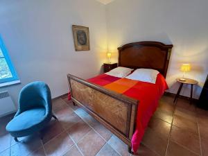 a bedroom with a bed and a blue chair at Charmante maison à Laure-Minervois avec piscine et jardin in Laure-Minervois