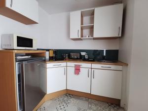 eine kleine Küche mit weißen Schränken und einer Mikrowelle in der Unterkunft Au Ptit Gauguin in Pont-Aven