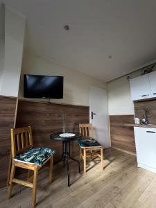 Il comprend une cuisine avec une table et deux chaises ainsi qu'une télévision murale. dans l'établissement Odlotowe noclegi, à Chełmno