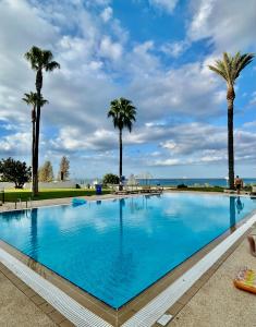 a large swimming pool with palm trees and the ocean at Paradise Apartment in Protaras