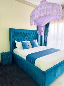 a blue bed with a purple canopy in a bedroom at Seil Apartment in Kampala