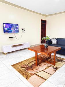 a living room with a table and a tv at Seil Apartment in Kampala