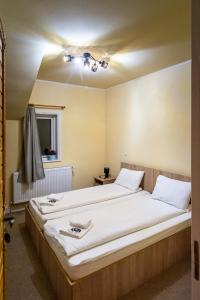 a bedroom with two beds with white sheets at Pensiunea Popas Pop, Strambu-Baiut, Maramures in Băiuţ