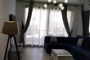 a living room with a blue couch in front of a window at 2 Bed Chalet Sleeps 4 Free Parking & Balcony in Ain Sokhna