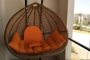 an orange chair with pillows in a hanging basket at 2 Bed Chalet Sleeps 4 Free Parking & Balcony in Ain Sokhna