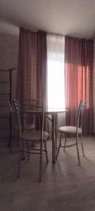 a dining room with a table and chairs and a window at Квартира посуточно Караганда in Karagandy