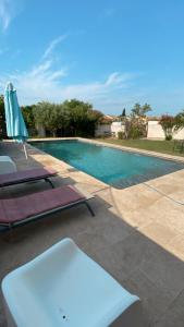 una piscina con 2 tumbonas junto a en La Maison des coeurs, en Vacqueyras