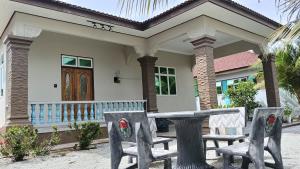a house with two chairs in front of it at Homestay Annur Barakah in Kampung Raja