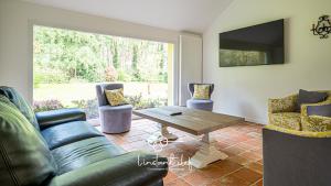 a living room with a couch and a table and chairs at Évasion Privée au Mans - Gîte Champêtre & Équestre in Guémardières
