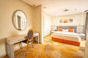 a bedroom with a bed and a desk and a mirror at Wahaj Boulevard Hotel Apartmentوهج بوليفارد للشقق الفندقية in Kuwait