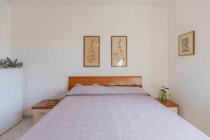 a bed in a bedroom with three pictures on the wall at Appartamento ElbaBlu by ElbaSummer Tour Operator in Lacona