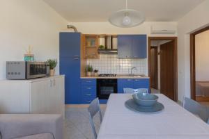 a kitchen with blue cabinets and a table with a bowl on it at Appartamento ElbaBlu by ElbaSummer Tour Operator in Lacona