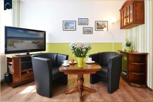een woonkamer met een tafel en stoelen en een televisie bij Haus Lindenstraße (051) An den Linden in Heringsdorf