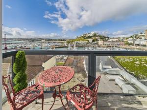 a balcony with a table and chairs and a view of a harbor at Harbour Haven Steps from Torquay Port in Torquay
