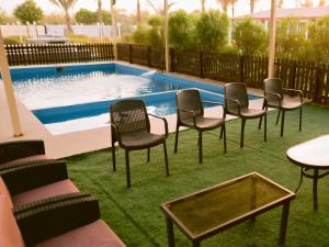 a group of chairs and tables in front of a pool at Palm Escape Farmhouse - By Seven Elements in Ras al Khaimah