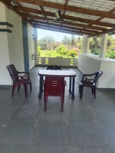 een patio met 2 stoelen en een tafel met een kat erop bij White House Home Stay! in Kaup