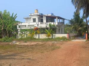 een wit huis aan de kant van een onverharde weg bij White House Home Stay! in Kaup