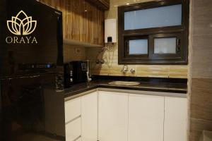 eine Küche mit einem schwarzen Kühlschrank und einer Spüle in der Unterkunft Modern & Bright Getaway in Madinaty in Banī Ghālib + 8 Fotos