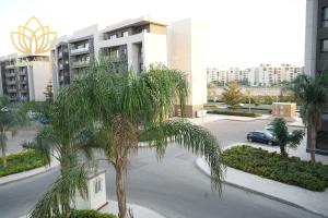 eine Palme auf einem Parkplatz vor einem Gebäude in der Unterkunft Modern & Bright Getaway in Madinaty in Banī Ghālib