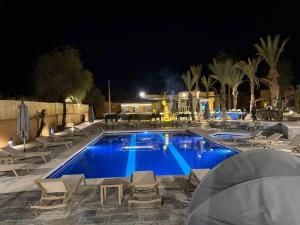 a swimming pool at night with chairs and a table at RS Hôtel Karam Resort in Ouarzazate