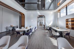 a restaurant with white tables and chairs and a mirror at Atour Light Hotel Shenzhen Guanlan Sany Cloud in Shenzhen