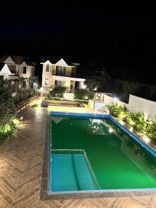 a swimming pool in front of a house at night at Comfort Stay Calangute beach Goa in Serula