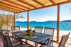 a table with a bowl of fruit on a deck with the ocean at Resort Šibenik in Šibenik