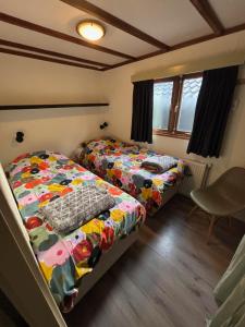 a bedroom with two beds and a chair in it at Chalet Wild Forest, knus chalet op de Veluwe met gratis parkeren in Putten