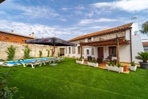 a yard with an umbrella and chairs and a pool at La Casa de Mi Madre casa rural con jacuzzi in La Parrilla