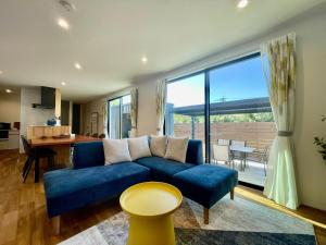 un salon avec un canapé bleu et une grande fenêtre dans l'établissement Lohas Resort 芥屋A, à Itoshima