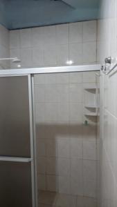 a white tiled bathroom with a shower and a sink at Hostel Ariramba in Belém
