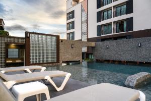 a swimming pool with two chairs and a building at Wangkaew Hotel, Phitsanulok in Phitsanulok