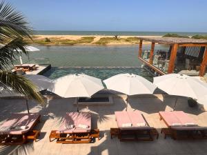 un grupo de sillas y sombrillas junto a una masa de agua en La Parenthèse, en Mbodiène