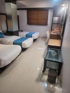 ein Hotelzimmer mit 3 Betten und einem Waschbecken in der Unterkunft Hotel sapphire regency in Vadodara
