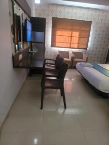 ein Schlafzimmer mit einem Schreibtisch, einem Bett und einem Stuhl in der Unterkunft Hotel sapphire regency in Vadodara + 6 Fotos