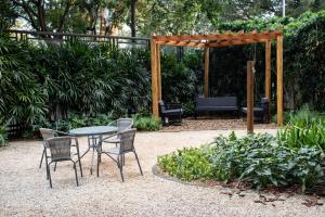 a table and chairs in a garden with a pergola at Modern apartment in Pinheiros and Faria Lima in Sao Paulo