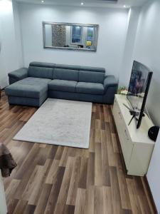 a living room with a blue couch and wooden floors at Riverside Central Apartment in Satu Mare