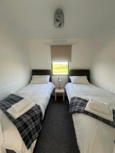 three twin beds in a room with a window at Caol Ila - Lodge 8 in Stranraer