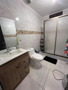 a bathroom with a toilet and a sink and a shower at Maitencillo, amplía y cómoda casa, con piscina y hoy tub in Puchuncaví +16 photos